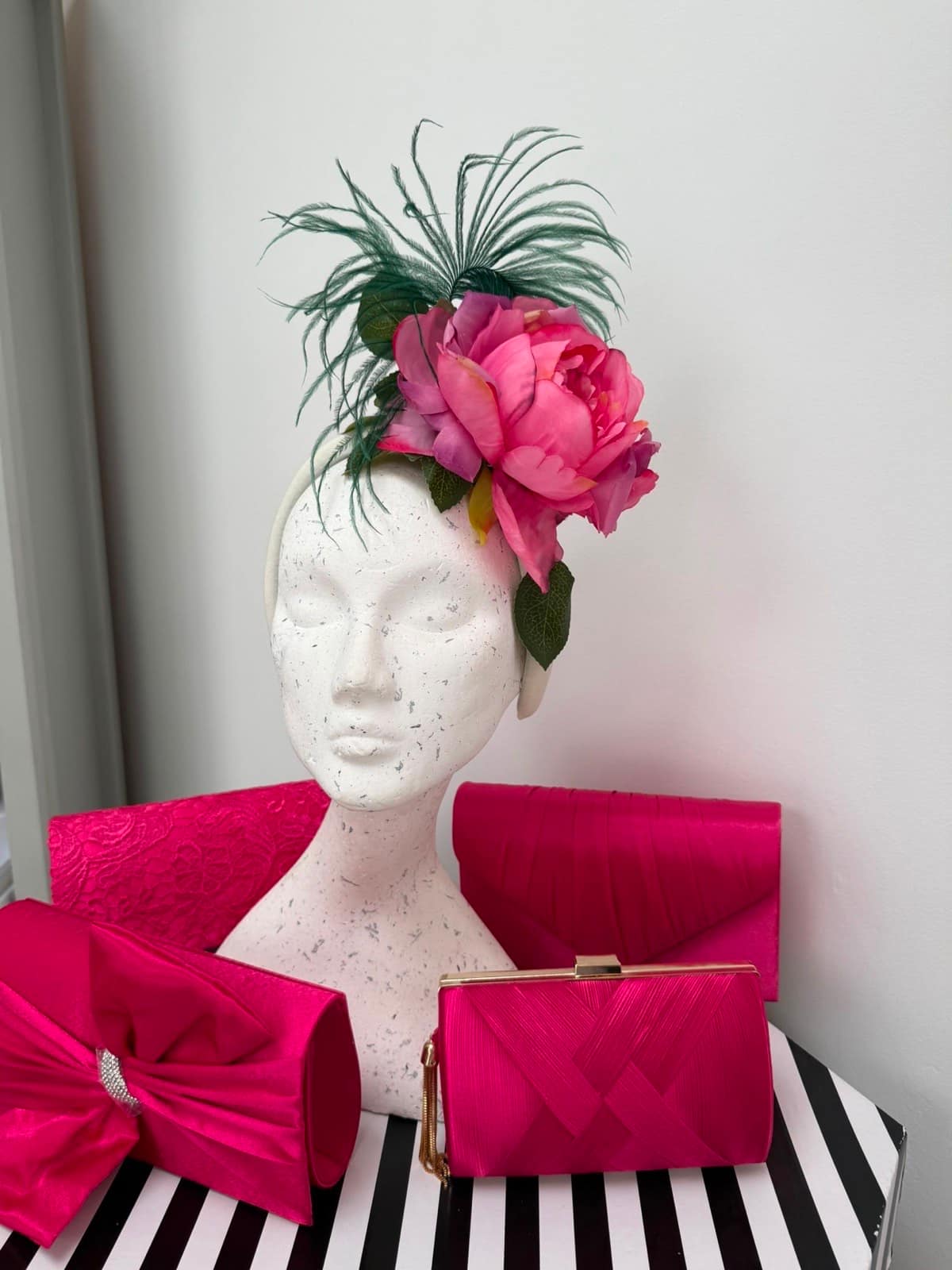 Pink peony headband with trailing green ostrich feathers, shown with hot pink clutch bags