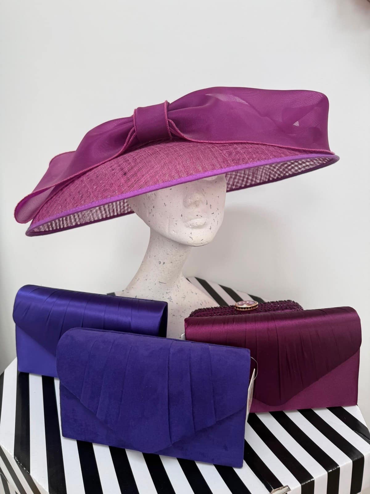 Magenta wide-brim hat with an organza bow, with purple suede and plum satin clutches