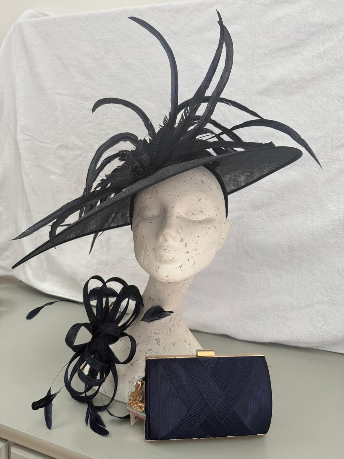 Navy wide-brim hatinator with dramatic feathers, navy loop fascinator and navy box clutch