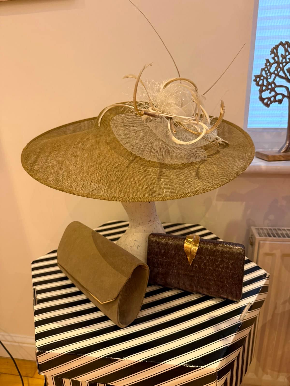 Olive gold wide-brim occasion hat with an ivory feather rosette, taupe suede clutch and bronze woven clutch