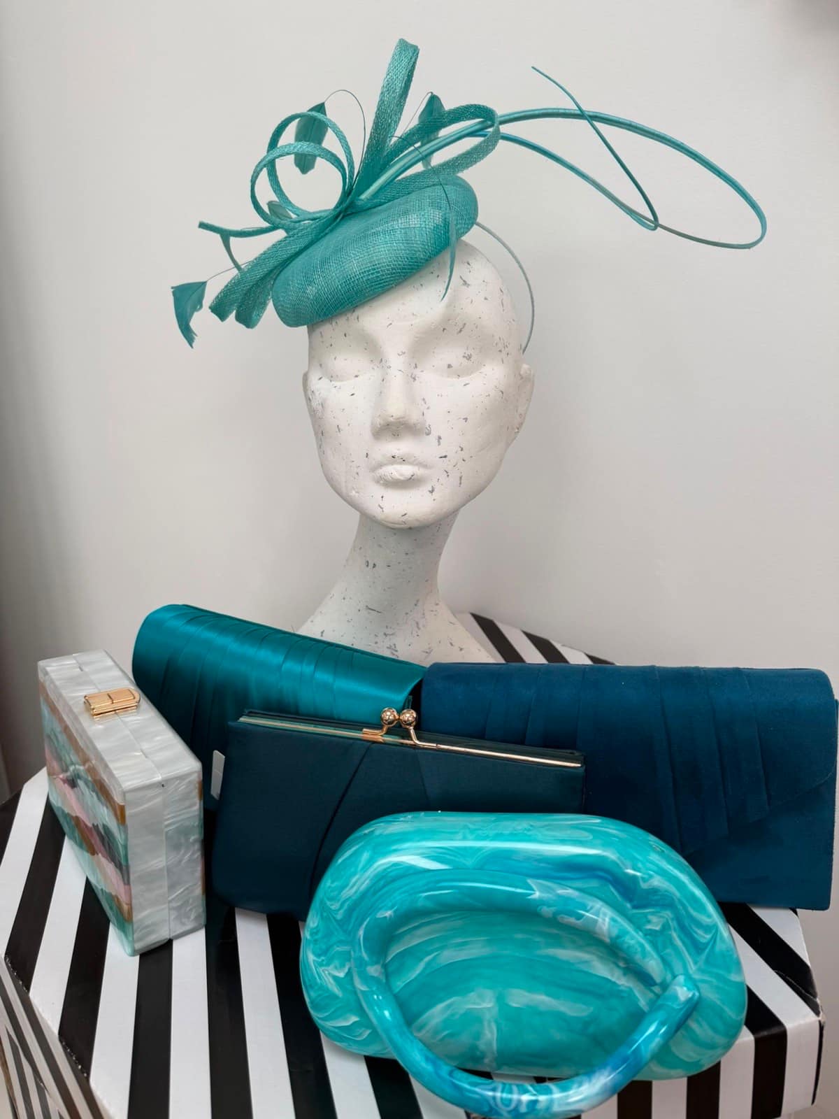 Aqua pillbox fascinator with sinamay loops and quills, shown with teal clutches, a pearl box clutch and a marbled aqua bag